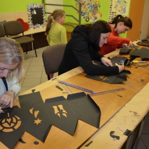 Zdjęcie przedstawia uczestników warsztatów rodzinnych podczas wykonywania swoich prac - lampionów adwentowych