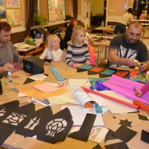 Zdjęcie przedstawia uczestników warsztatów rodzinnych podczas wykonywania swoich prac - lampionów adwentowych