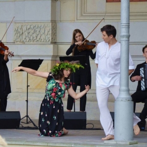 Zdjęcie przedstawia artystów na scenie amfiteatru w świerklanieckim parku podczas koncertu pt. W drogę ruszamy dookoła świata