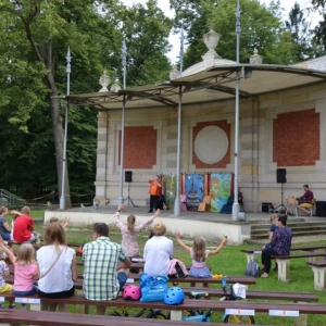 Zdjęcie przedstawia publiczność oraz amfiteatr w świerklanieckim parku w trakcie przedstawienia teatralnego