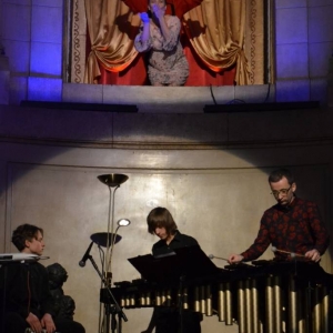 Zdjęcie przedstawia występujących artystów w witrynie okiennej oraz u szczytu schodów  wewnątrz Pałacu Kawalera,  podczas koncertu pt. Percussio