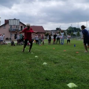 Zdjęcie przedstawia uczestników półkolonii podczas wspólnej zabawy na boisku sportowym