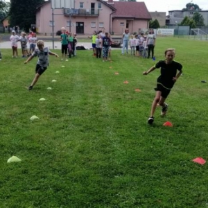 Zdjęcie przedstawia uczestników półkolonii podczas wspólnej zabawy na boisku sportowym