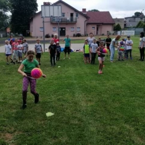 Zdjęcie przedstawia uczestników półkolonii podczas wspólnej zabawy na boisku sportowym