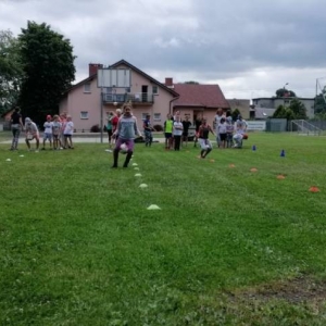 Zdjęcie przedstawia uczestników półkolonii podczas wspólnej zabawy na boisku sportowym