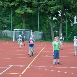 Zdjęcie przedstawia uczestników półkolonii podczas wspólnej zabawy na boisku sportowym