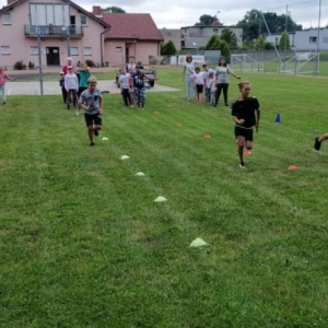 Zdjęcie przedstawia uczestników półkolonii podczas wspólnej zabawy na boisku sportowym