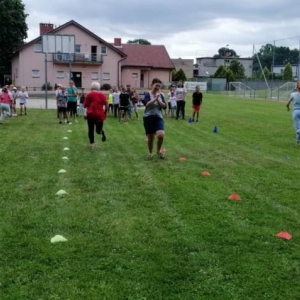 Zdjęcie przedstawia uczestników półkolonii podczas wspólnej zabawy na boisku sportowym