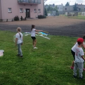 Zdjęcie przedstawia uczestników półkolonii podczas wspólnej zabawy na boisku sportowym