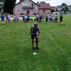 Zdjęcie przedstawia uczestników półkolonii podczas wspólnej zabawy na boisku sportowym