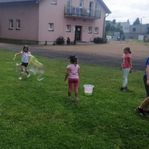 Zdjęcie przedstawia uczestników półkolonii podczas wspólnej zabawy na boisku sportowym