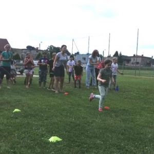 Zdjęcie przedstawia uczestników półkolonii podczas wspólnej zabawy na boisku sportowym