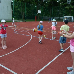 Zdjęcie przedstawia uczestników półkolonii podczas wspólnej zabawy na boisku sportowym