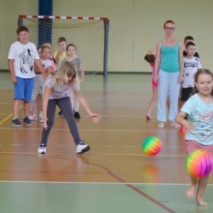 Zdjęcie przedstawia uczestników półkolonii na hali sportowej 