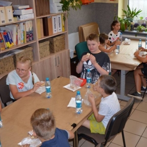 Zdjęcie przedstawia uczestników półkolonii podczas słodkiego poczęstunku