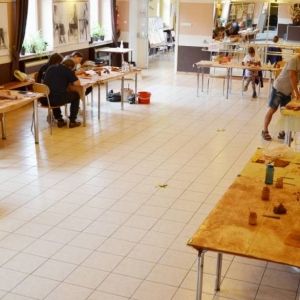 Zdjęcie przedstawia uczestników warsztatów ceramicznych podczas wykonywania swoich prac