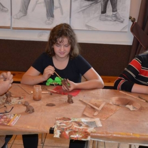 Zdjęcie przedstawia uczestników warsztatów ceramicznych podczas wykonywania swoich prac