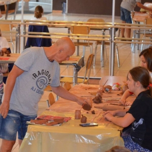 Zdjęcie przedstawia uczestników warsztatów ceramicznych podczas wykonywania swoich prac