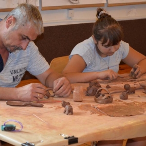 Zdjęcie przedstawia uczestników warsztatów ceramicznych podczas wykonywania swoich prac