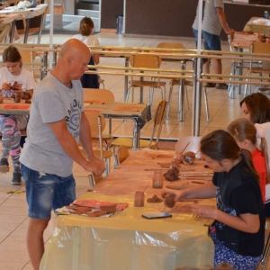 Zdjęcie przedstawia uczestników warsztatów ceramicznych podczas wykonywania swoich prac