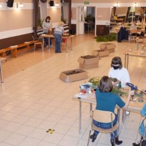 Zdjęcie przedstawia uczestrników warsztatów podczas wykonywania stroików świątecznych