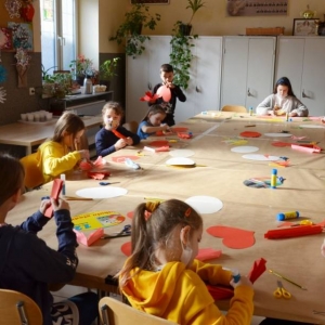 Zdjęcie przedstawia uczestników półkolonii podczas pracy plastycznej - robienie walentynek