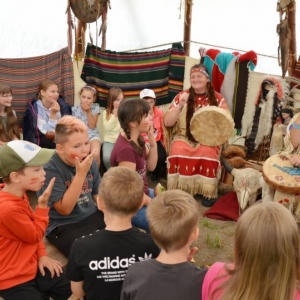 Drugiego dnia uczestnicy półkolonii odwiedzili wioskę indiańską w Karchowicach. Zdjęcie przedstawia dzieci podczas wspólnej zabawy w wiosce indiańskiej.