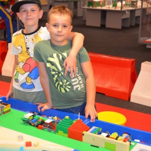 Zdjęcie przedstawia uczestników półkolonii IV turnusu w trakcie wycieczki na wystawę klocków LEGO podczas zwiedzania i wspólnej zabawy. 