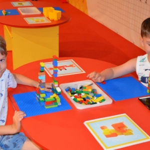 Zdjęcie przedstawia uczestników półkolonii IV turnusu w trakcie wycieczki na wystawę klocków LEGO podczas zwiedzania i wspólnej zabawy. 