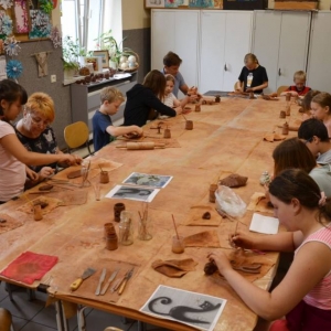 Zdjęcie przedstawia uczestników warsztatów ceramicznych podczas wykonywania swoich prac