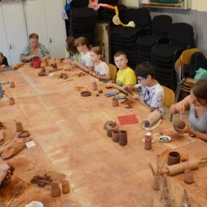 Zdjęcie przedstawia uczestników warsztatów ceramicznych podczas wykonywania swoich prac