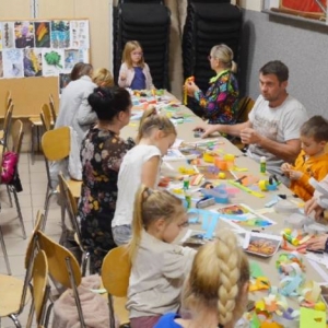 Zdjęcie przedstawia uczestników Rodzinnych Warsztatów Świątecznych podczas wykonywania choinkowych ozdób z papieru 