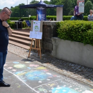 Zdjęcie przedstawia konkurs rysowania kredą na asfalcie