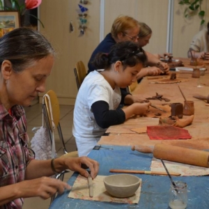 Zdjęcie przedstawia uczestników warsztatów podczas wykonywania swoich prac ceramicznej