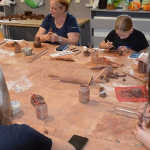 Zdjęcie przedstawia uczestników warsztatów podczas wykonywania swoich prac ceramicznej
