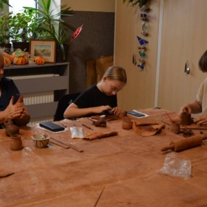 Zdjęcie przedstawia uczestników warsztatów podczas wykonywania swoich prac ceramicznej