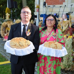 Starości dożynkowi z chlebami przed sceną na tle wieńców dożynkowych