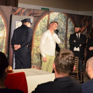 Aktorzy na scenie podczas spektaklu. Przed sceną publiczność.