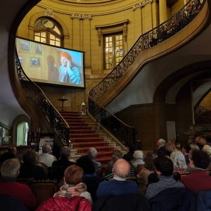 Publiczność podczas projekcji filmu w Pałacu Kawalera w Świerklańcu. Przed publicznością ekran projekcyjny z wyświetlanym filmem.