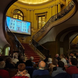 Publiczność podczas projekcji filmu w Pałacu Kawalera w Świerklańcu. Przed publicznością ekran projekcyjny z wyświetlanym filmem.