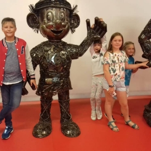 Zdjęcie przedstawia uczestników półkolonii podczas wizyty w Galerii Figur Stalowych