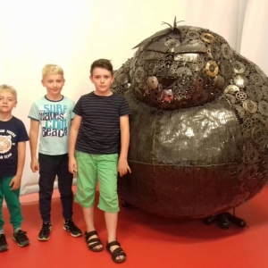 Zdjęcie przedstawia uczestników półkolonii podczas wizyty w Galerii Figur Stalowych