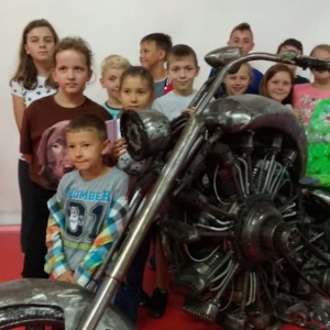 Zdjęcie przedstawia uczestników półkolonii podczas wizyty w Galerii Figur Stalowych