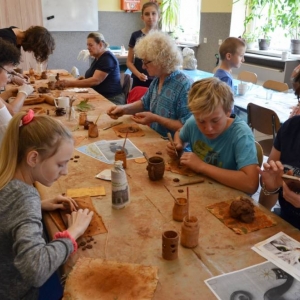 Zdjęcie przedstawia uczestników warsztatów ceramicznych podczas wykonywania swoich prac