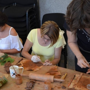Zdjęcie przedstawia uczestników warsztatów ceramicznych podczas wykonywania swoich prac