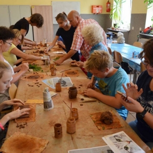 Zdjęcie przedstawia uczestników warsztatów ceramicznych podczas wykonywania swoich prac
