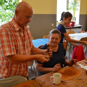 Zdjęcie przedstawia uczestników warsztatów ceramicznych podczas wykonywania swoich prac
