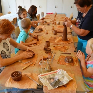 Zdjęcie przedstawia uczestników warsztatów ceramicznych podczas wykonywania swoich prac