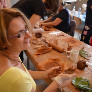 Zdjęcie przedstawia uczestników warsztatów ceramicznych podczas wykonywania swoich prac