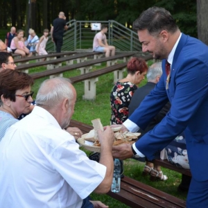 Zdjęcie przedstawia Wójta Gminy Świerklaniec Marka Cyla częstującego chlebem publiczność dożynkową